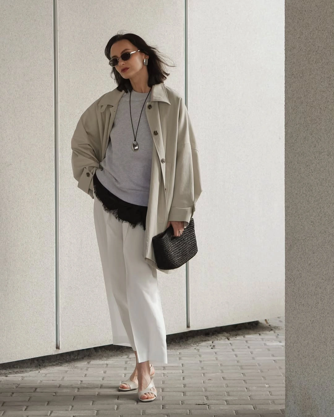 Beige overshirt, gray top, cropped pale trousers, and dark fringed detail