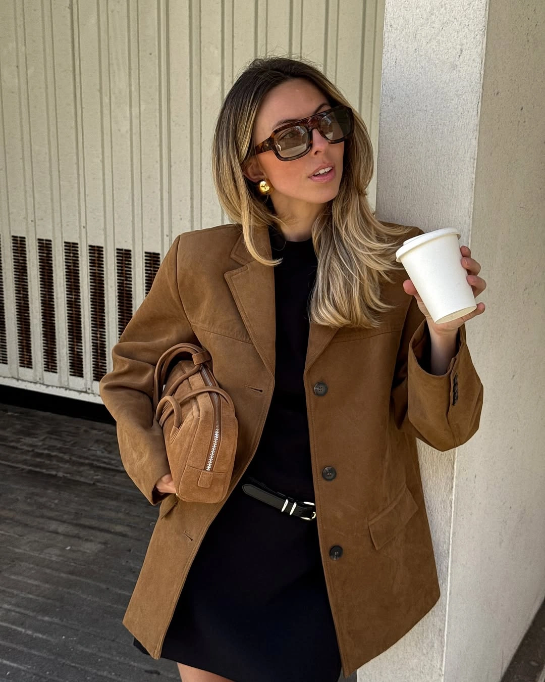 Camel brown jacket over black outfit with matching brown shoulder bag