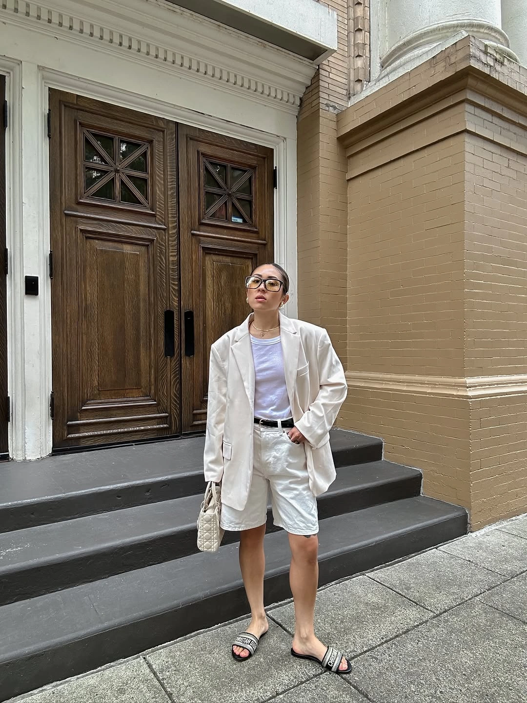 Oversized pale blazer with white shirt, light shorts, and striped sandals