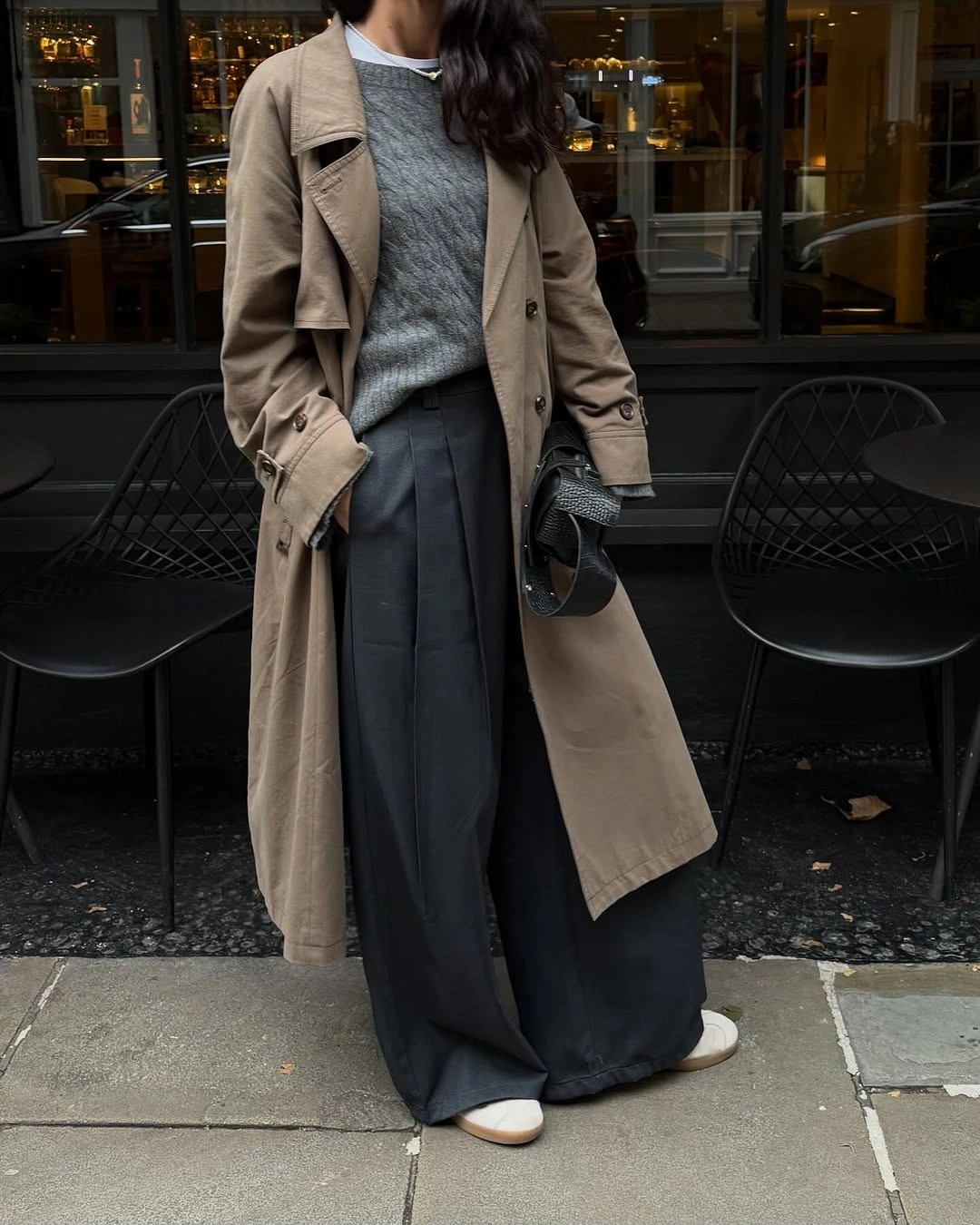 Beige trench coat over gray top and wide charcoal pleated trousers