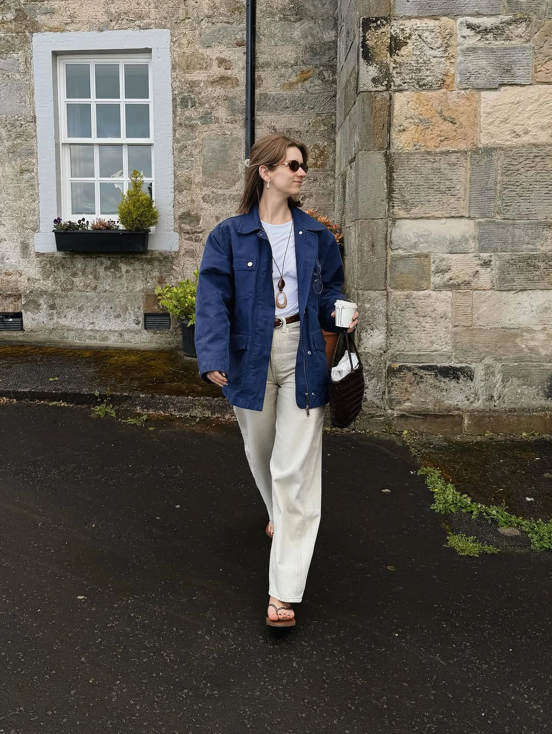 Blue boxy jacket with white shirt, pale trousers, and brown sandals
