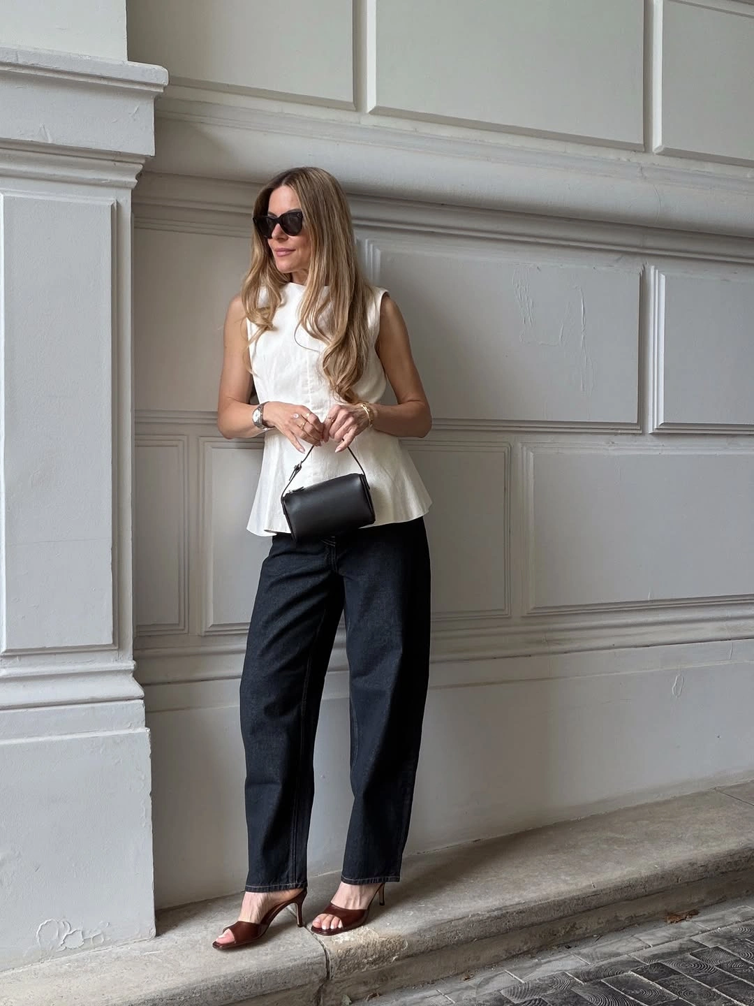 White sleeveless flared top with dark trousers and red heels