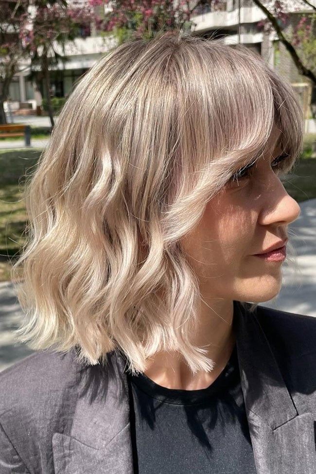 Collarbone Bob With Wavy Beige Blonde Balayage And Side Part Collarbone Bob With Wavy Beige Blonde Balayage And Side Part — Classy Bob with Curtain Bangs