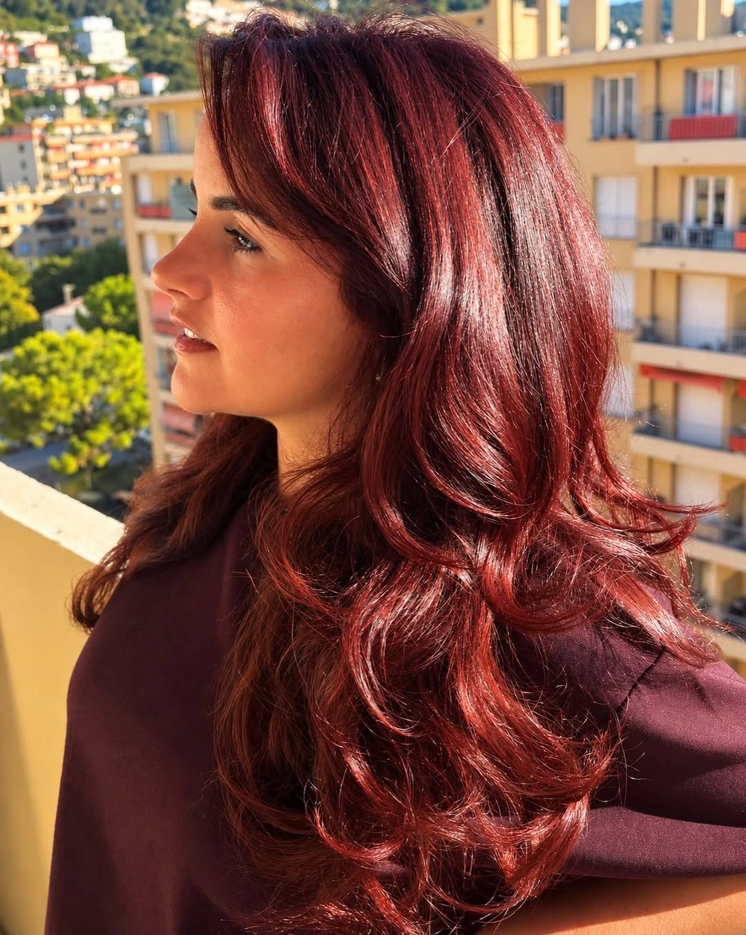 Long cherry red hair with ruby reflections and sweeping layered waves