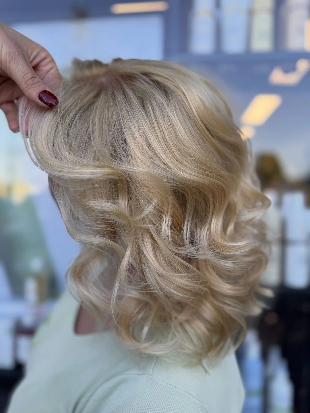 Short champagne blonde hair with beige roots and voluminous curled layers