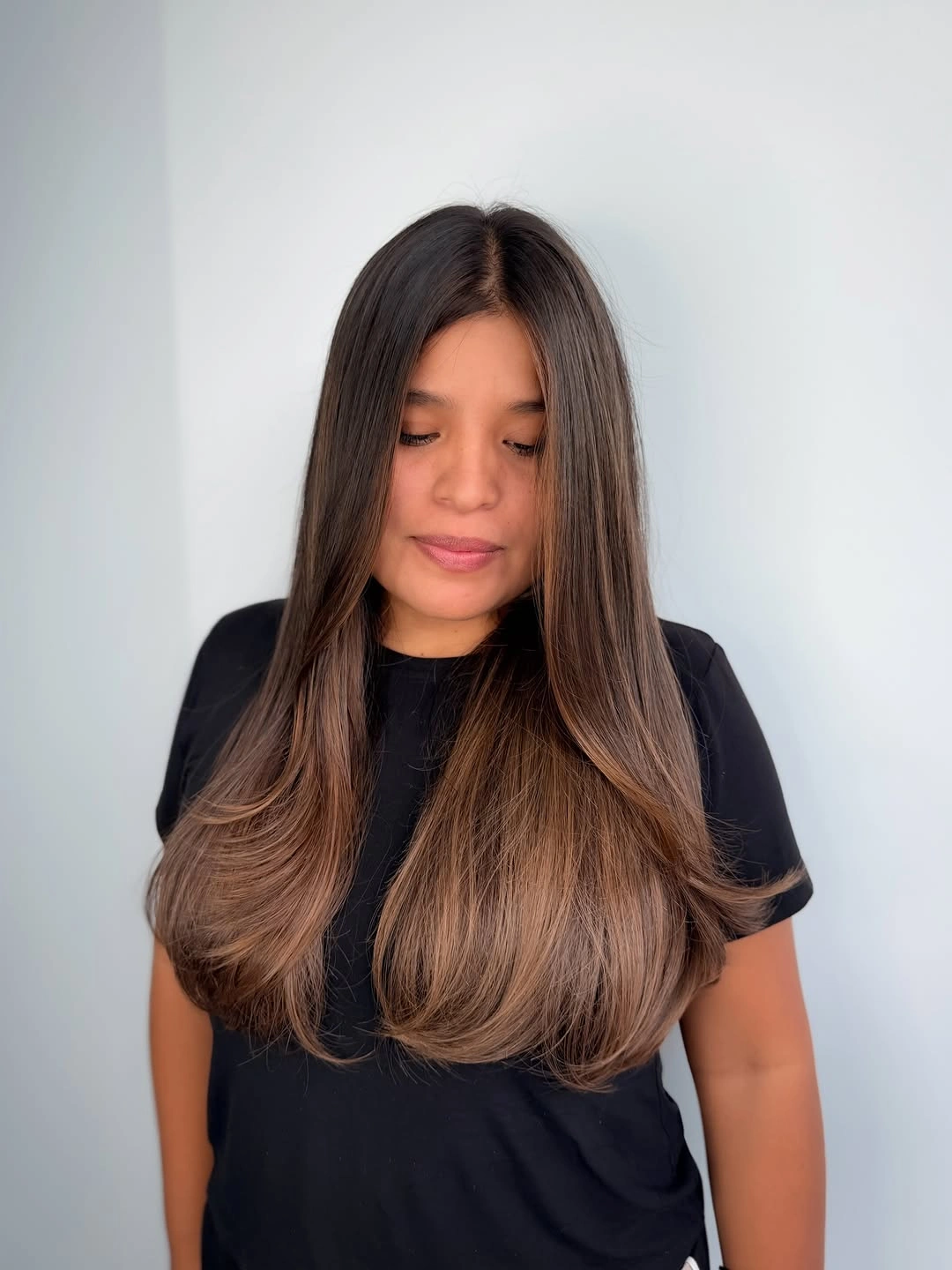 Long center-parted brown hair with warmer caramel lengths and curved ends