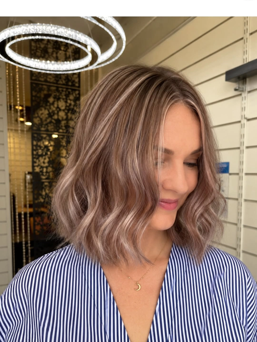 Shoulder-length taupe brown wavy bob with pale beige face-framing highlights