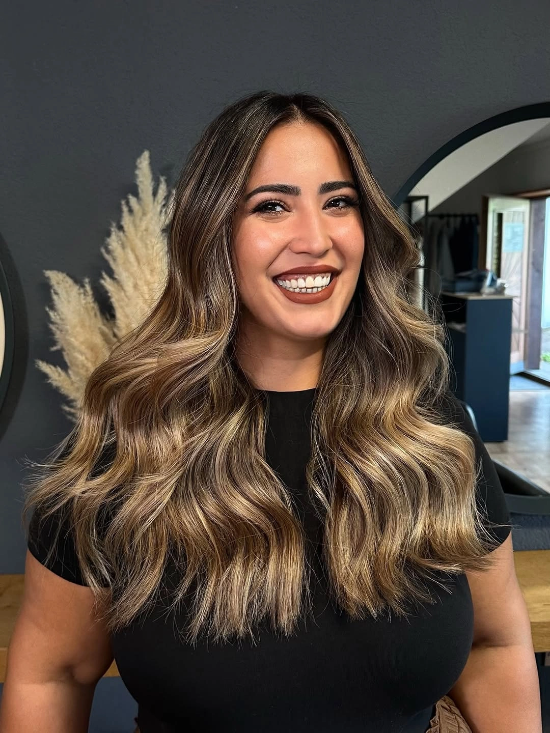 Long dark brown waves with honey beige highlights through the lower lengths