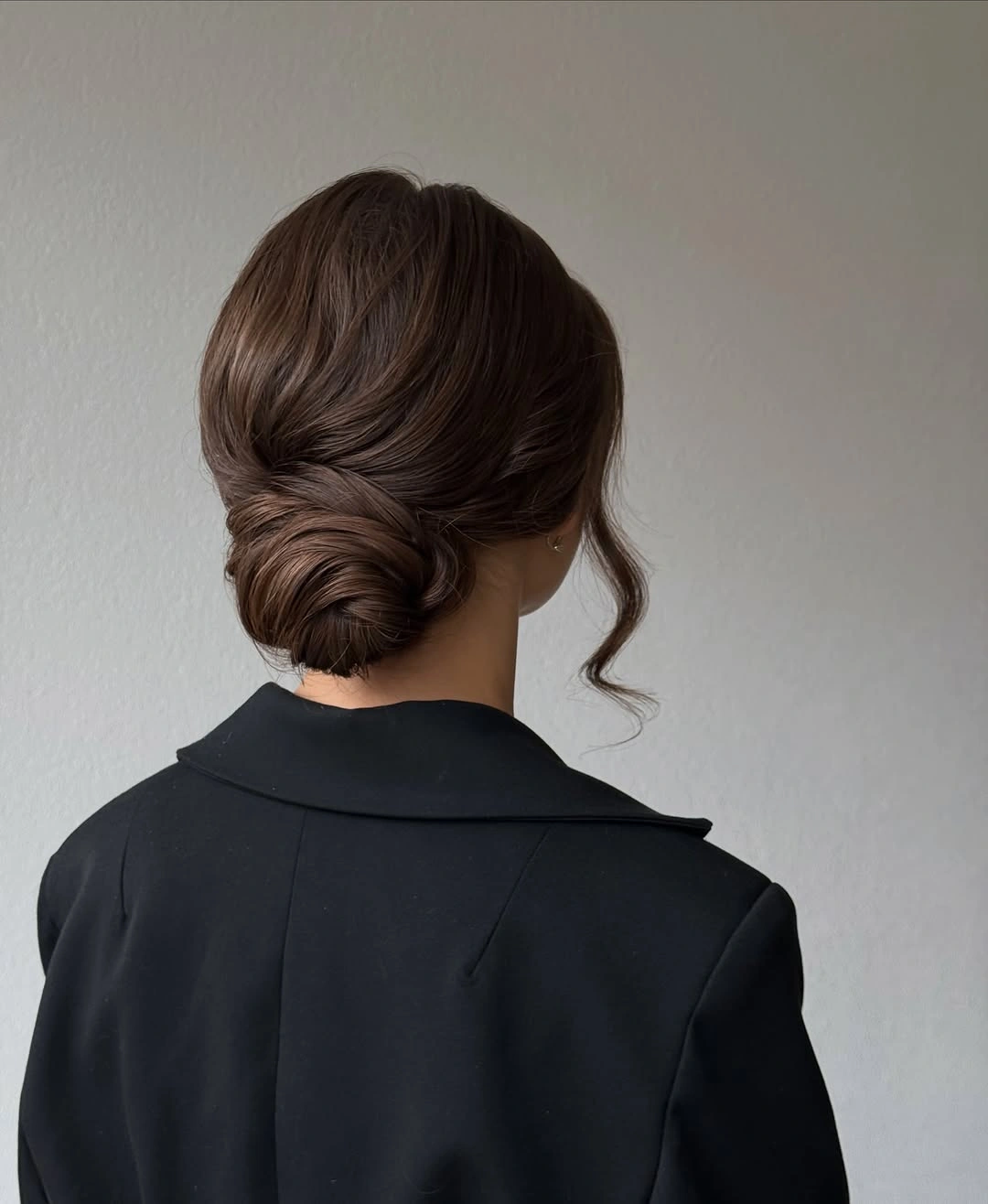 Brunette wrapped low bun with one curled face-framing tendril