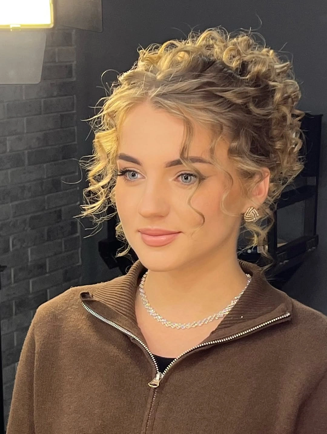 Blonde curly updo with lifted curls and loose face-framing pieces