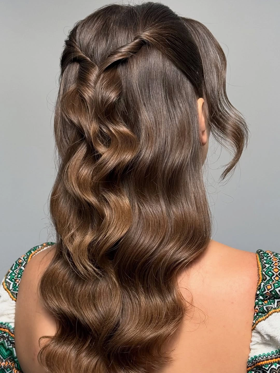 Long brunette waves with twisted half-up sections meeting at center