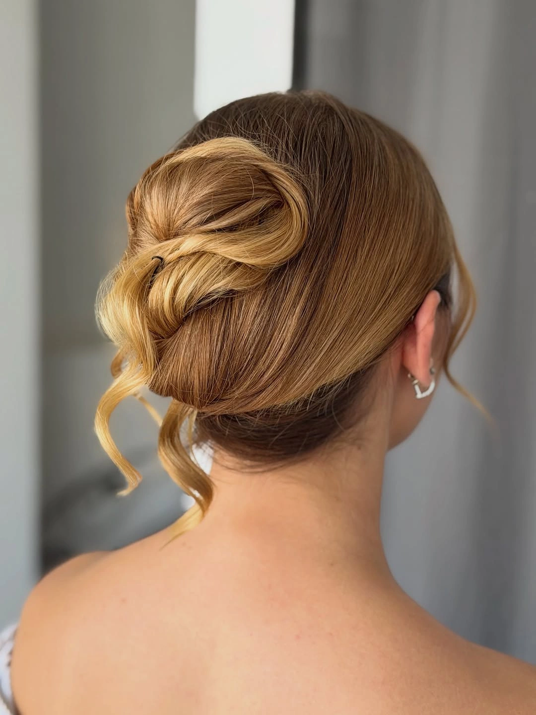 Blonde wrapped low updo with curled face-framing tendrils