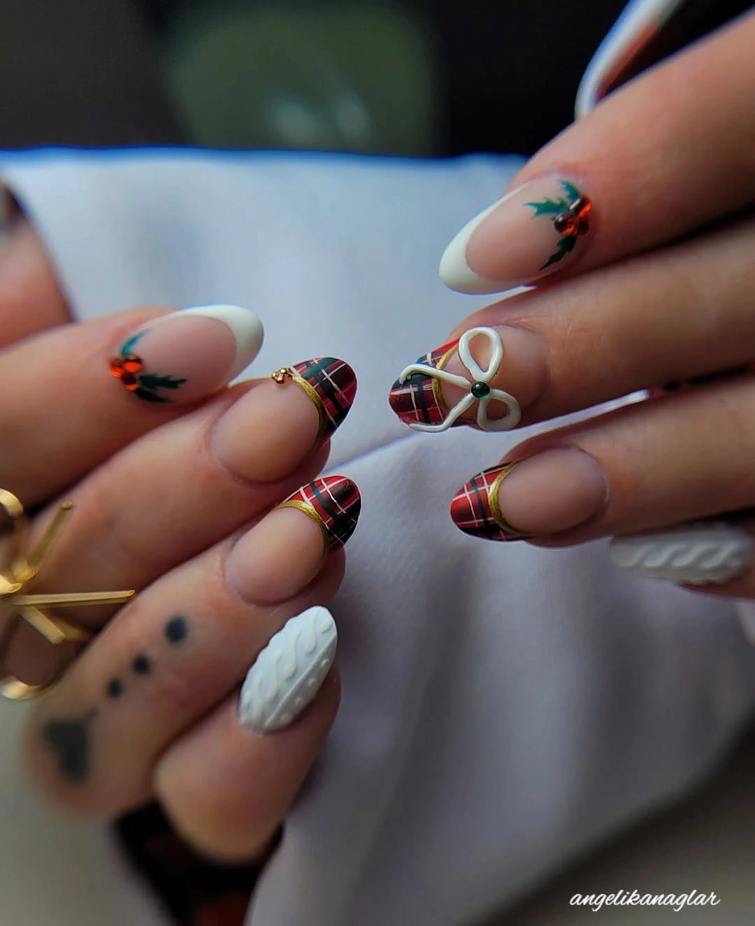 Almond nails with red plaid French tips, holly details, and white knit texture