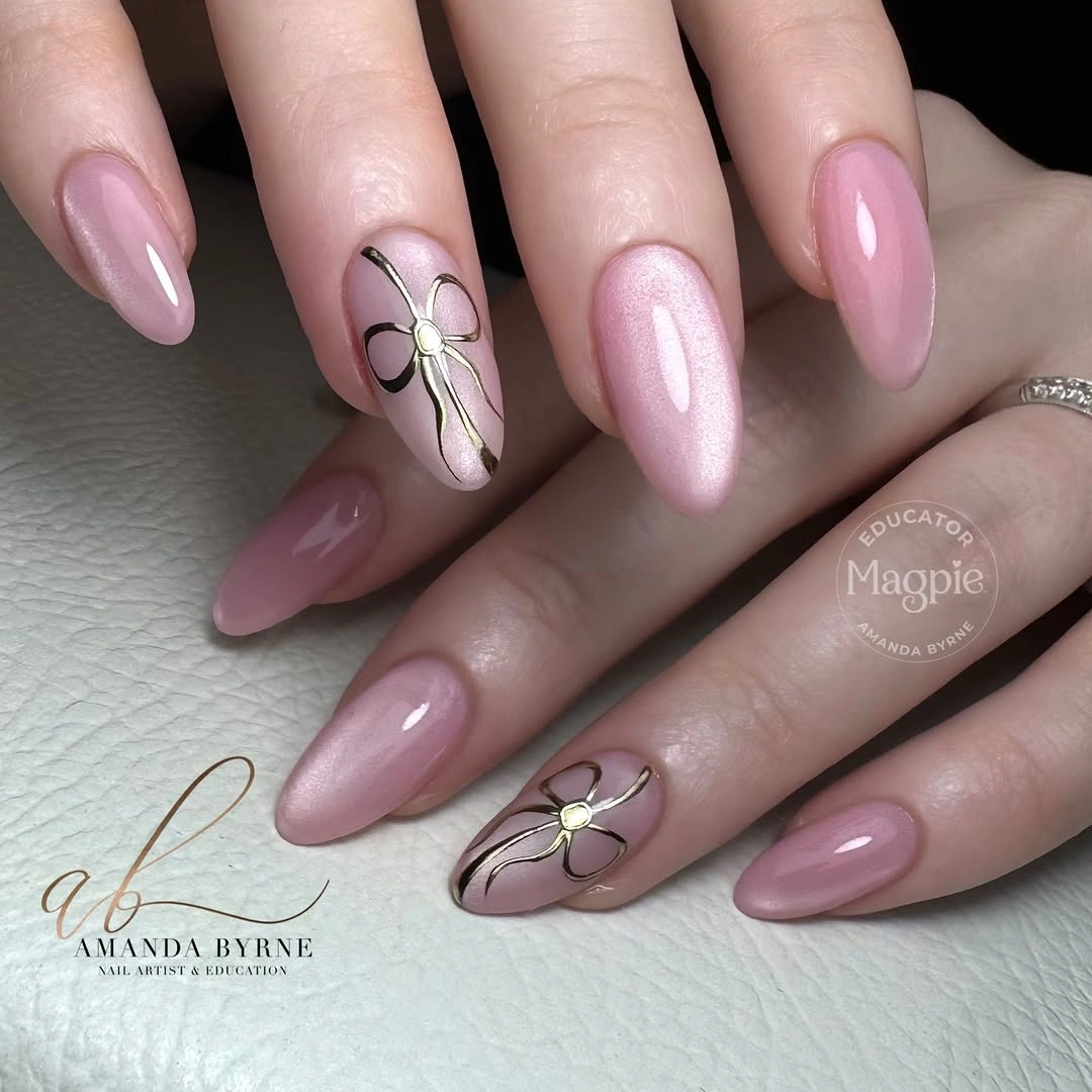 Pink almond nails with pearl shimmer and large black outlined ribbon bows