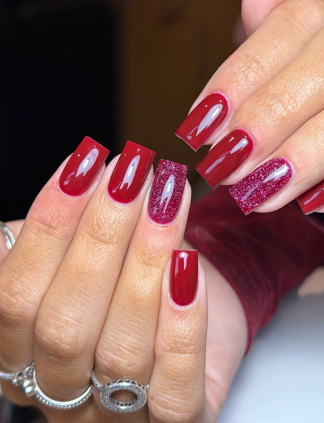 Long square cherry red nails with glossy polish and raspberry glitter accents