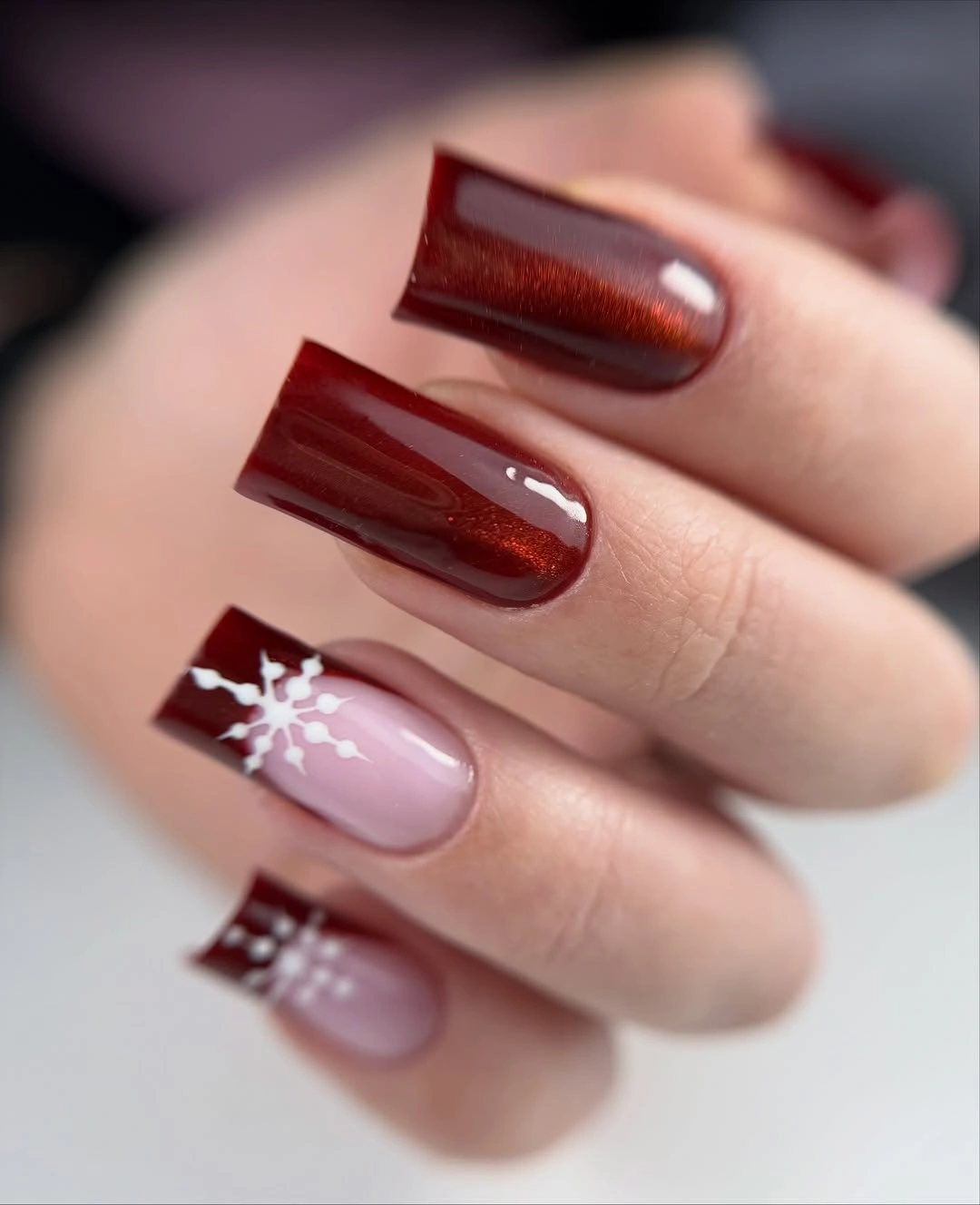 Long square burgundy nails with copper shimmer and white snowflake French tips