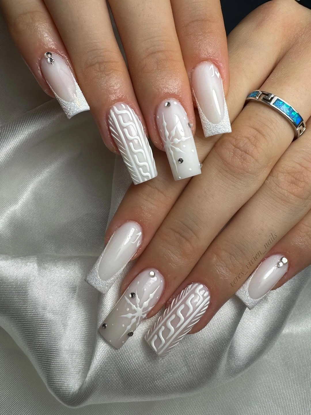 Long square white nails with cable patterns, snowflakes, and glitter French tips