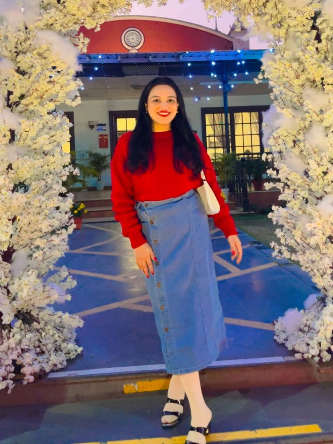 Woman in red sweater, blue buttoned denim midi skirt and black sandals