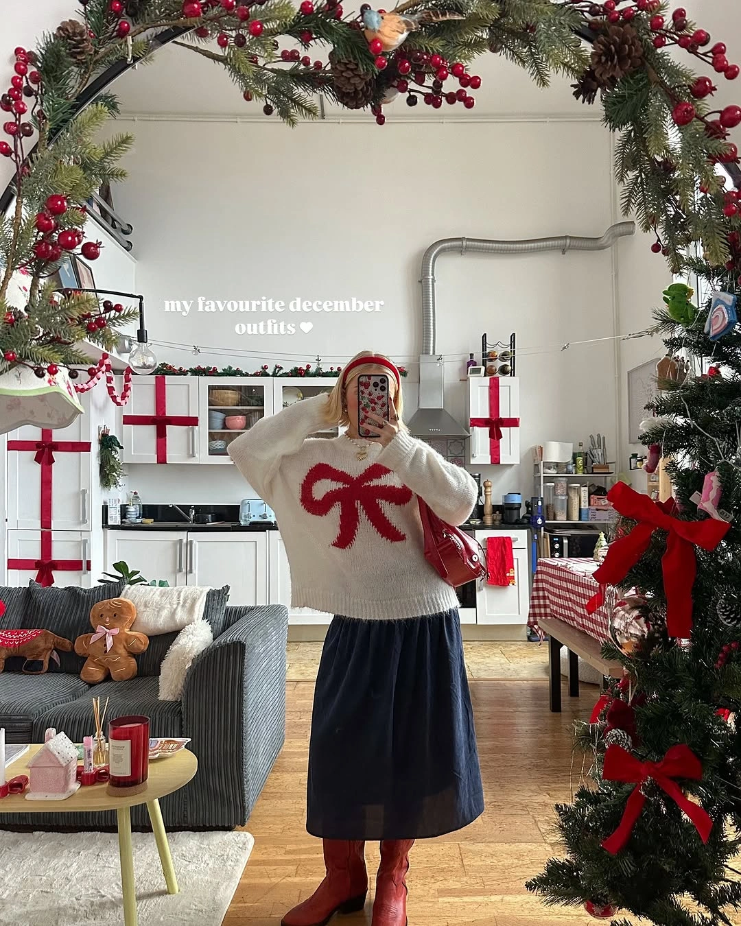 Woman in cream red-bow sweater, dark midi skirt, red headwear and boots