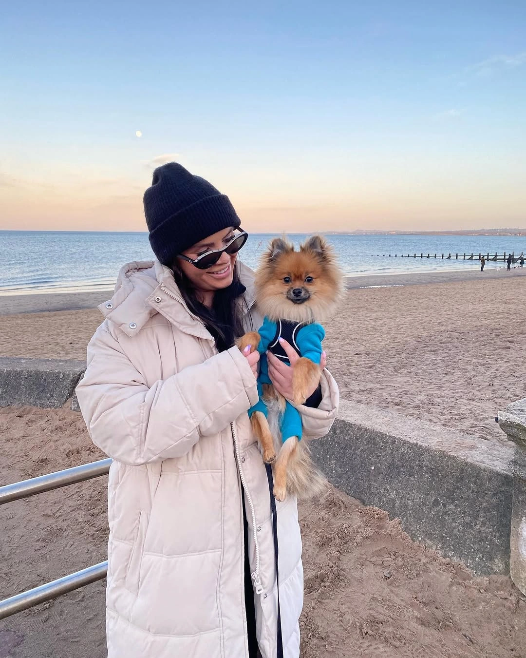 Long ivory quilted puffer coat with dark beanie and narrow sunglasses