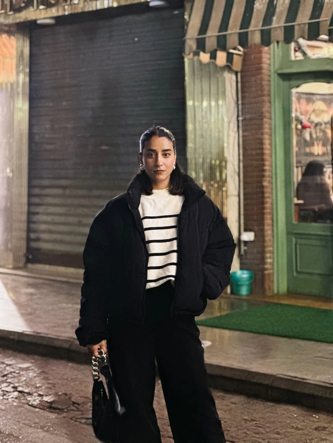 Oversized black puffer jacket with striped cream top and wide black trousers