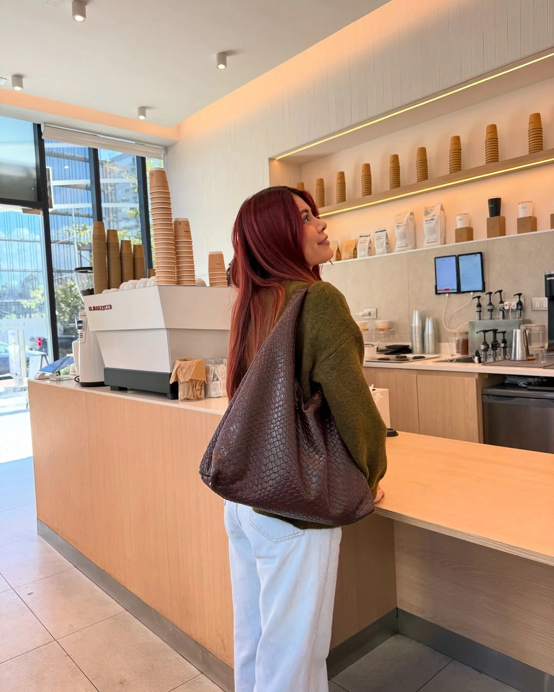 Olive sweater and pale blue jeans with oversized textured brown shoulder bag