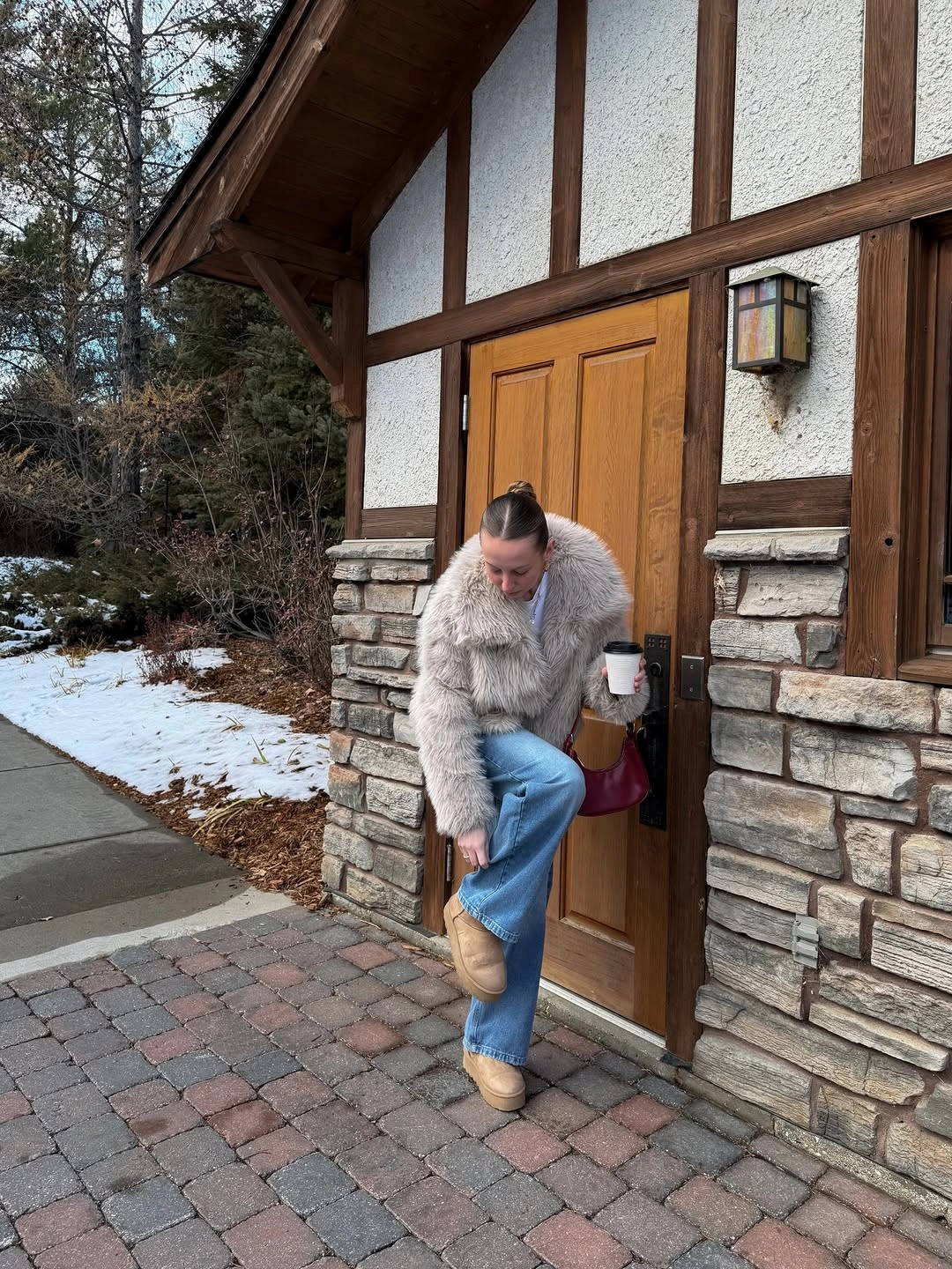 Short gray plush jacket with blue jeans, tan boots, and burgundy bag