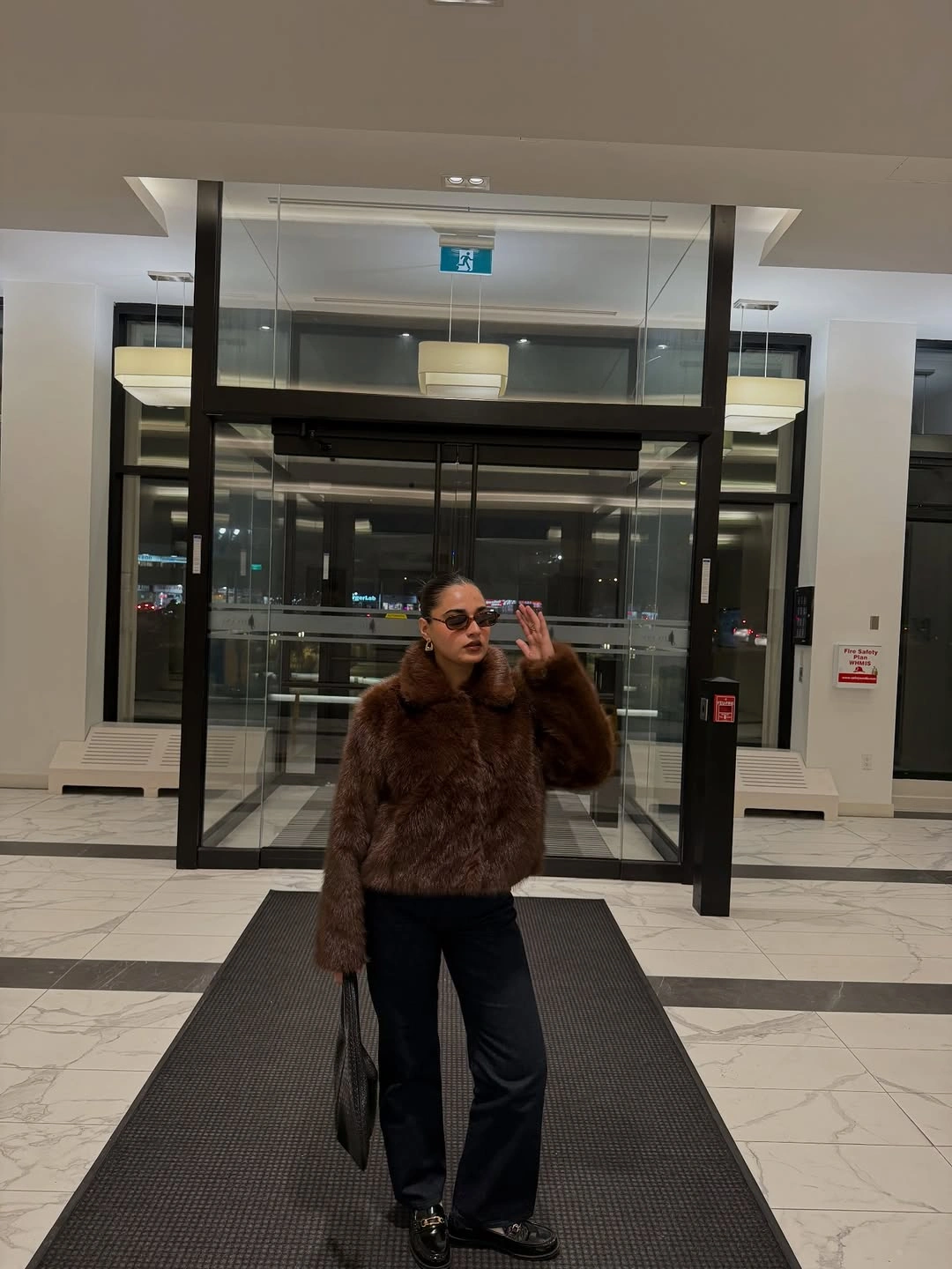 Cropped fuzzy brown jacket with wide black trousers, sunglasses, and dark shoes