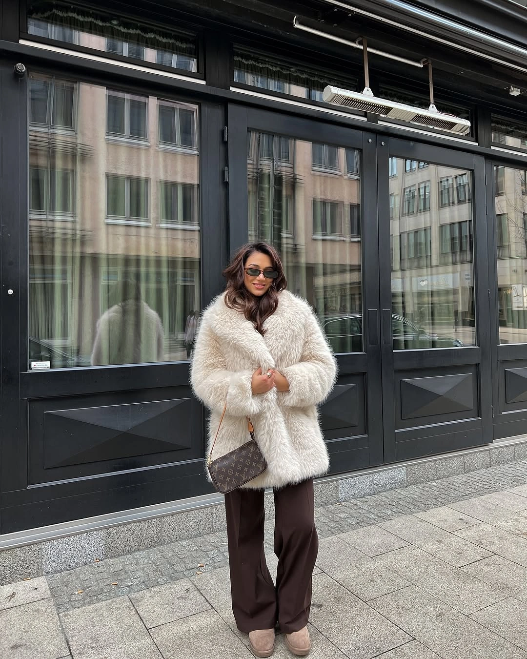 Cream textured coat with brown wide-leg trousers and patterned shoulder bag