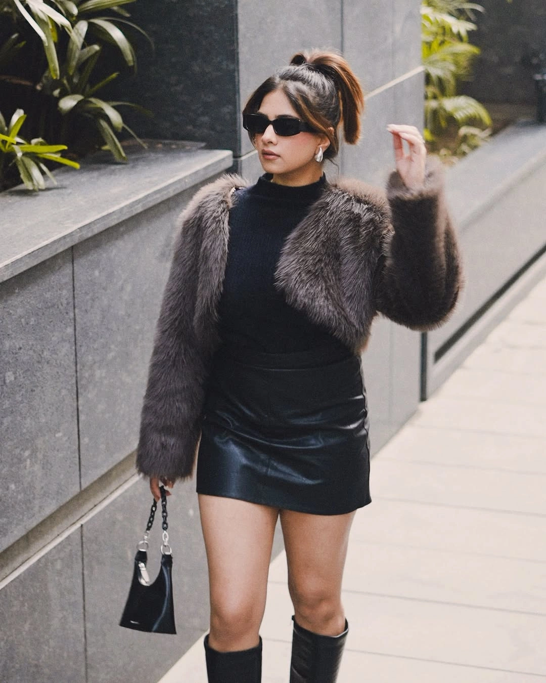 Gray brown textured jacket over black top, glossy mini skirt, and tall boots