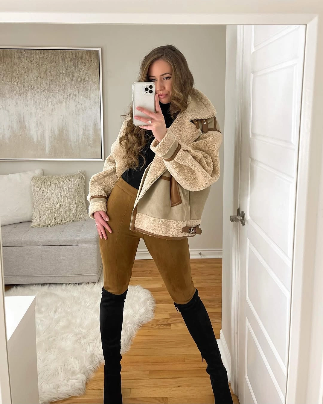 Beige shearling-style jacket with brown trousers and tall black boots