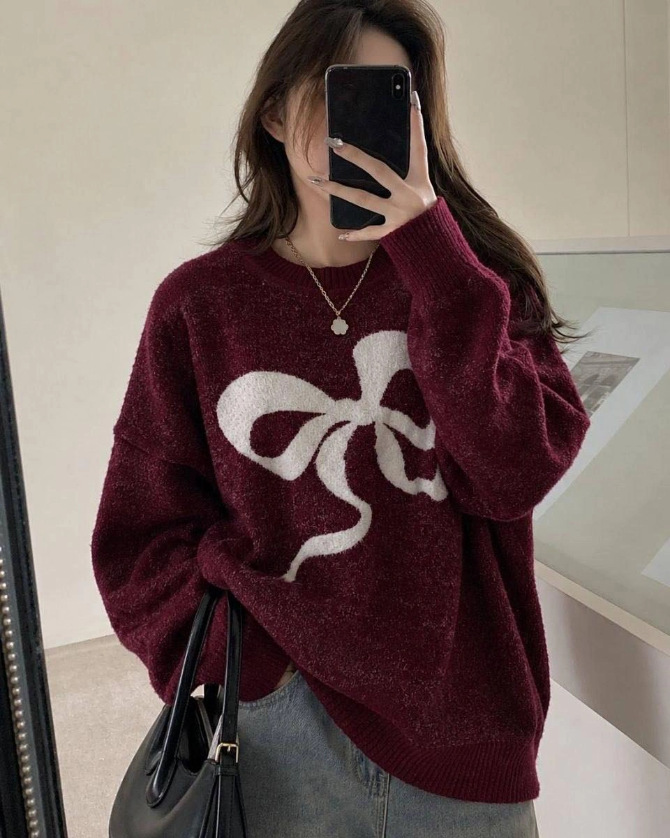 Burgundy oversized sweater with white bow graphic gray jeans and black handbag
