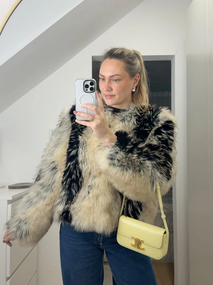 Cream and black shaggy jacket with blue jeans and pale yellow shoulder bag