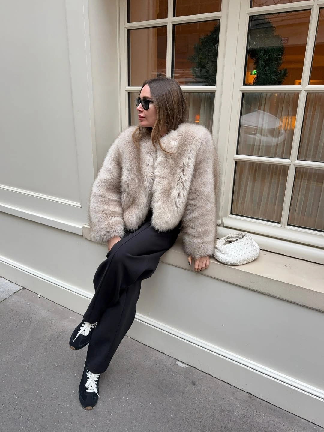 Pale plush looking jacket with black wide trousers and white laced sneakers