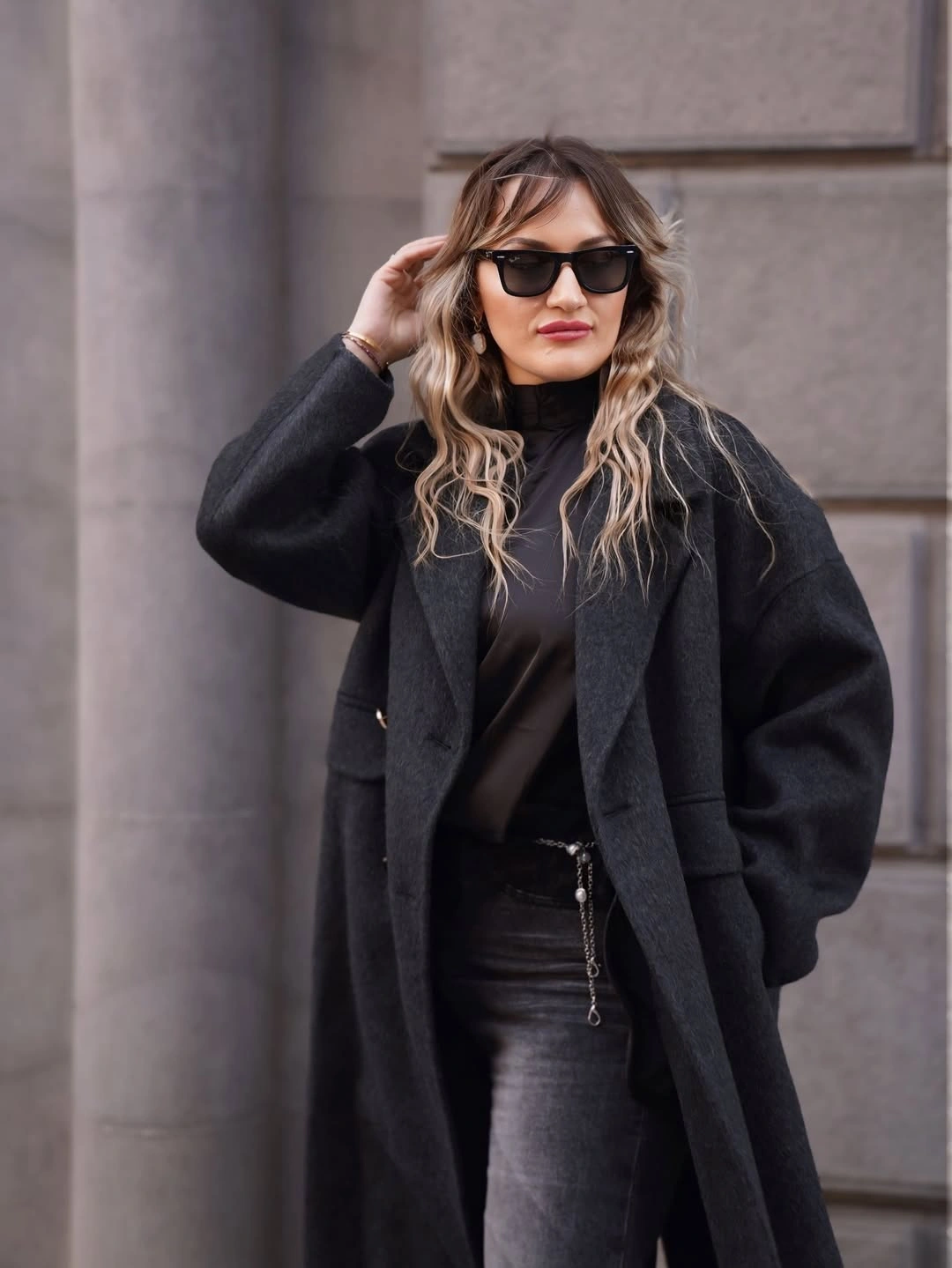 Long charcoal black coat over dark high neck top and leather look trousers