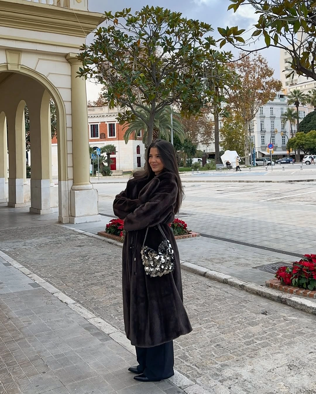 Long dark textured coat over wide trousers with reflective embellished shoulder bag