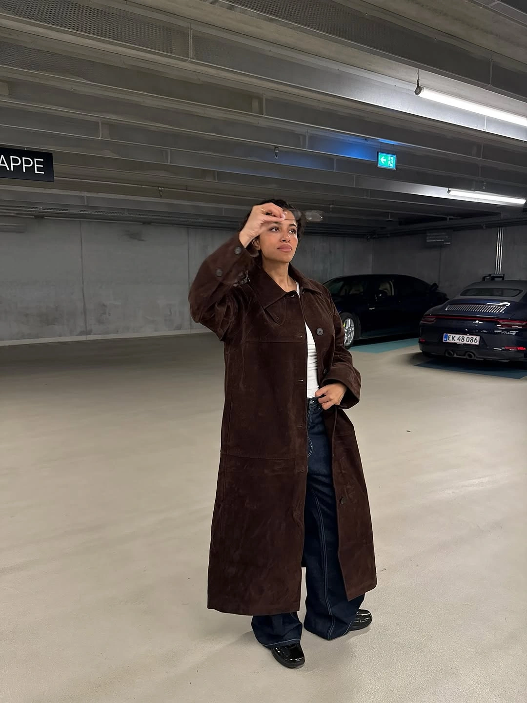Long chocolate-brown coat with dark wide-leg jeans and black shoes.