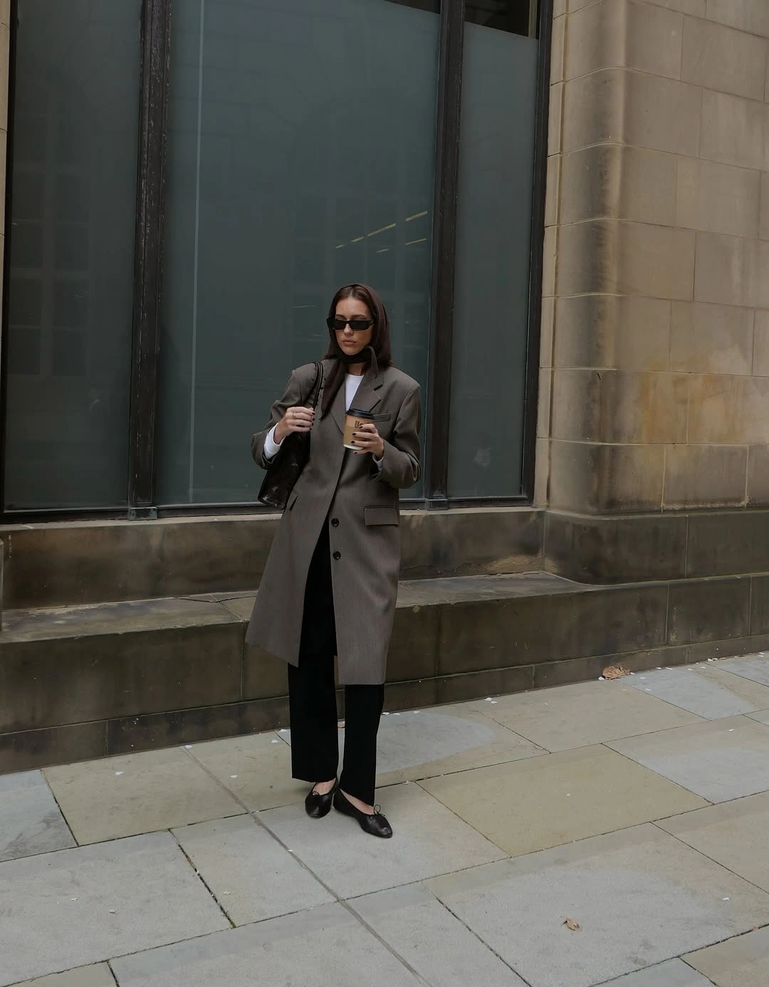 Gray tailored coat with dark inner layers, black trousers, and sunglasses.