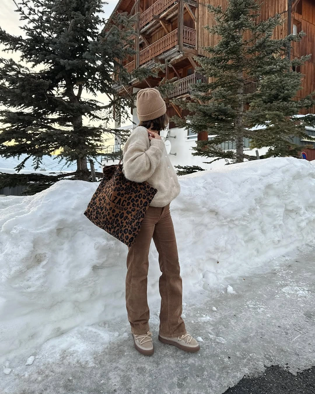 Cream fuzzy sweater, brown trousers, knit beanie, leopard tote, and sneakers.