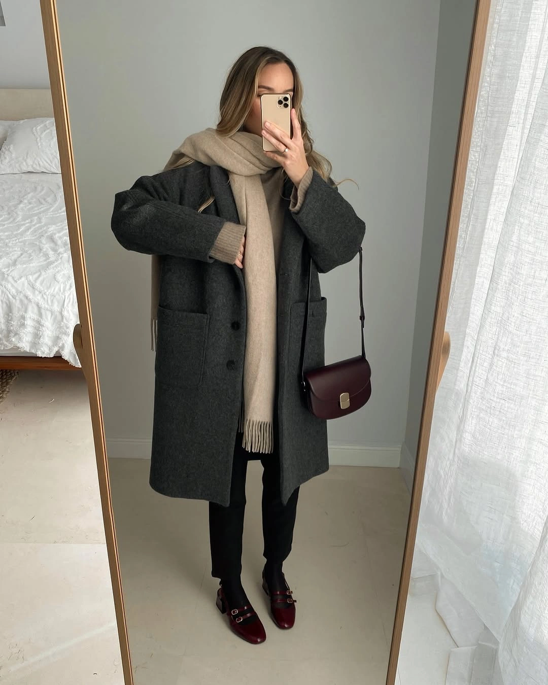 Charcoal coat, beige scarf, black trousers, burgundy flats, and matching handbag.