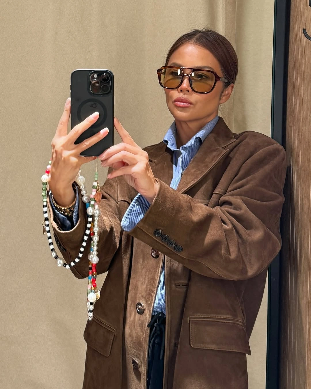 Oversized brown blazer layered over blue collared shirt with tinted sunglasses.