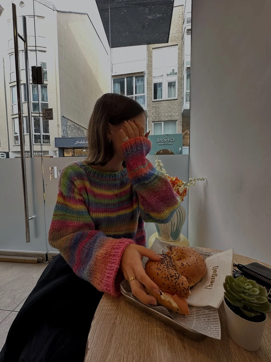 Multicolored striped sweater with broad sleeves and dark flowing lower silhouette
