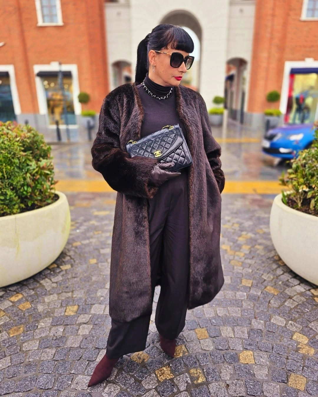 Long dark brown textured coat black outfit quilted handbag and burgundy boots