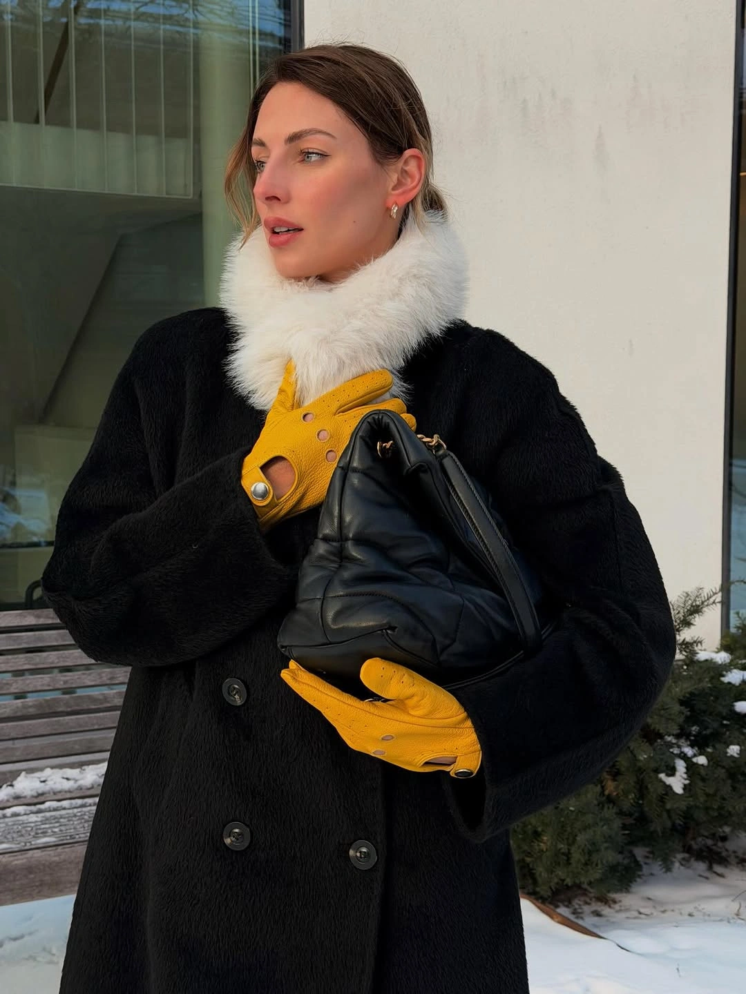 Black double breasted coat white fluffy neck wrap yellow gloves and padded handbag