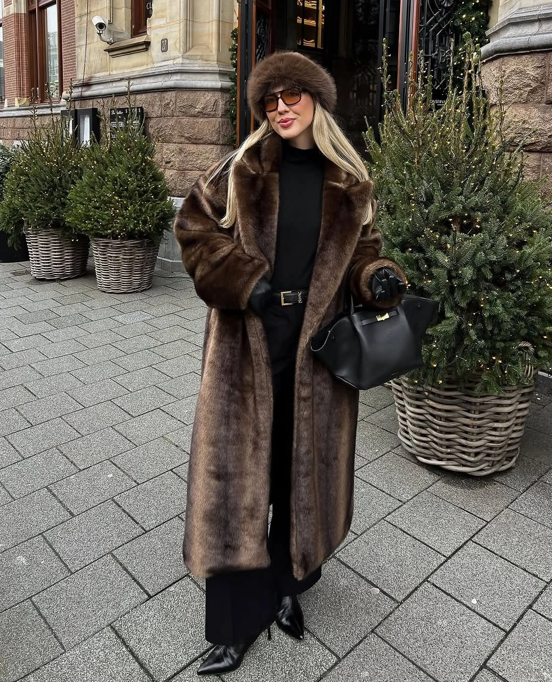Long brown textured coat matching fluffy hat black boots and handbag