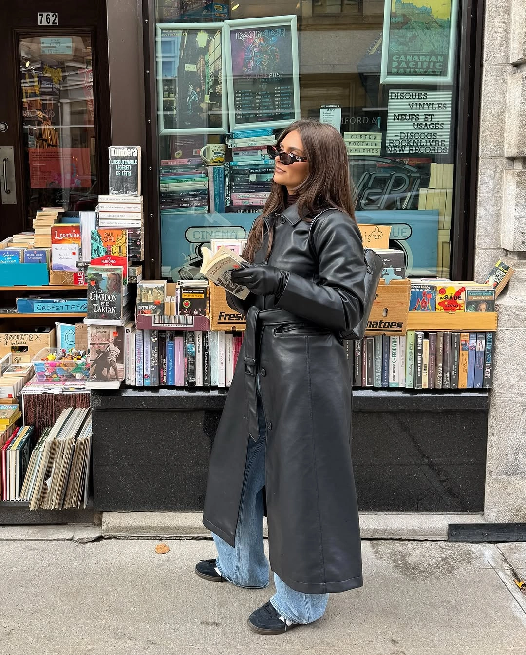 Long black belted coat with light blue jeans gloves and sunglasses