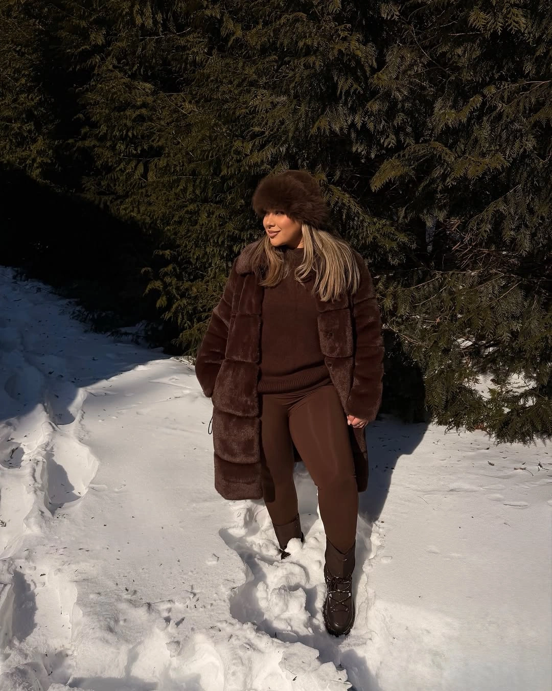Long brown textured coat matching rounded hat dark pants and lace up boots
