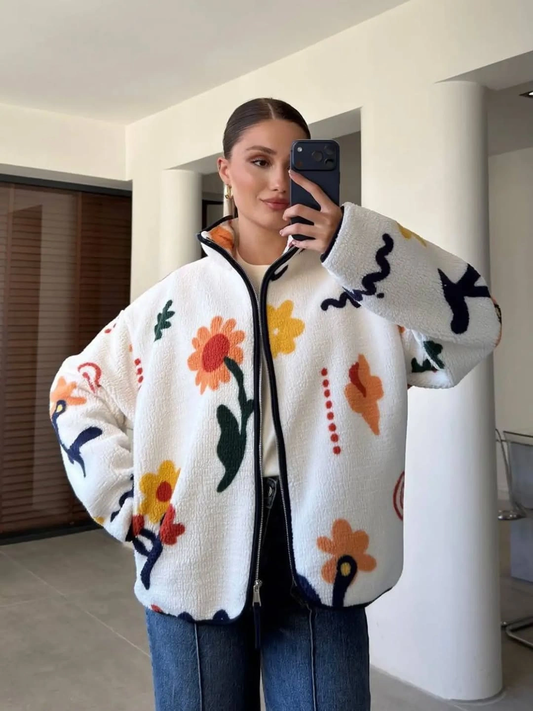 Oversized white zip jacket with colorful floral motifs and blue jeans