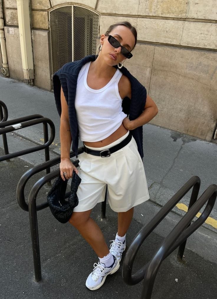 White Tailored Shorts With Navy Sweater Draped Over Shoulders — Trendy Basic Outfits