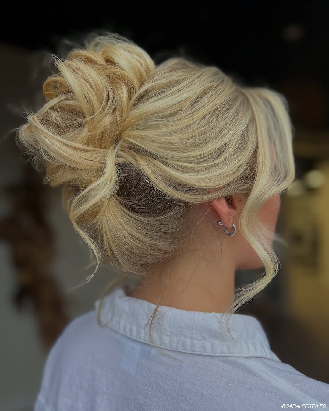 Intricate Blonde Bun With Loose Wavy Tendrils — Trendy High Bun Hairstyles